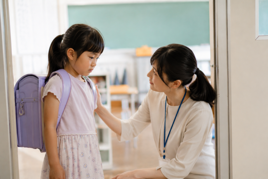 夏休み明け 行きたくない 教室の入り口で子どもに声をかける先生