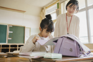忘れ物が多い子 対応 ランドセルの持ち物を確認する小学生と教師